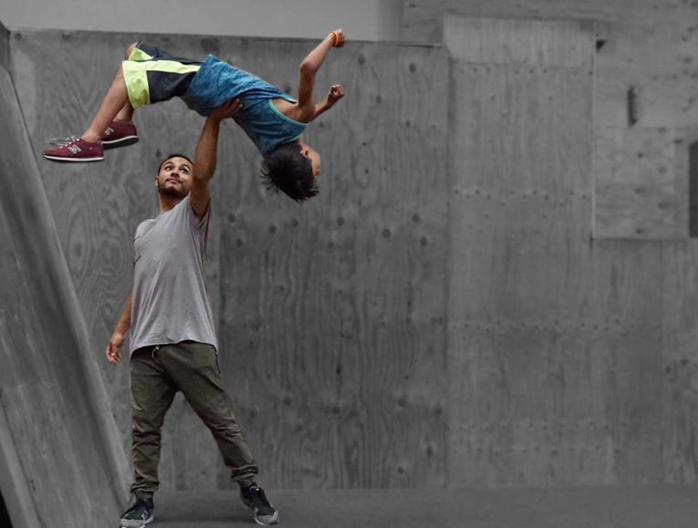 A man and boy are doing tricks on the skateboard ramp.